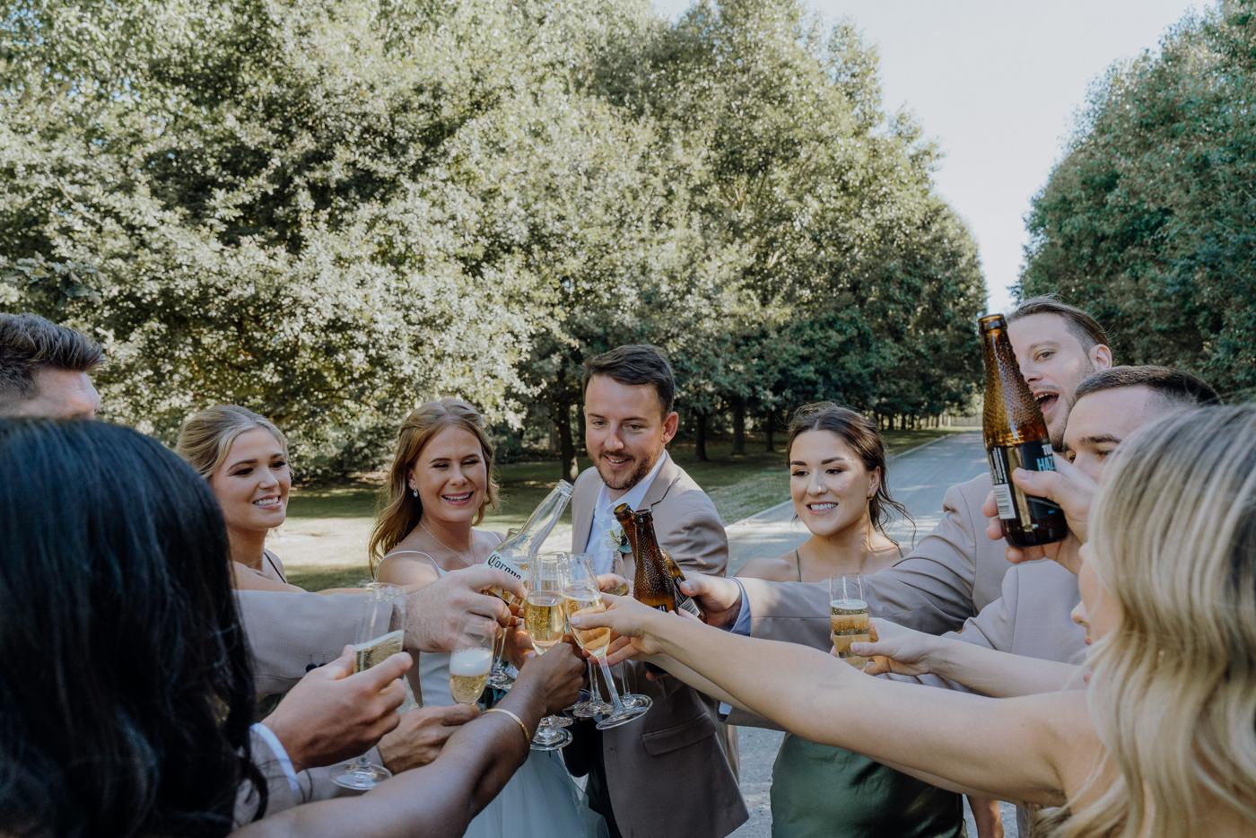 Bridal party raising drinks together under the trees