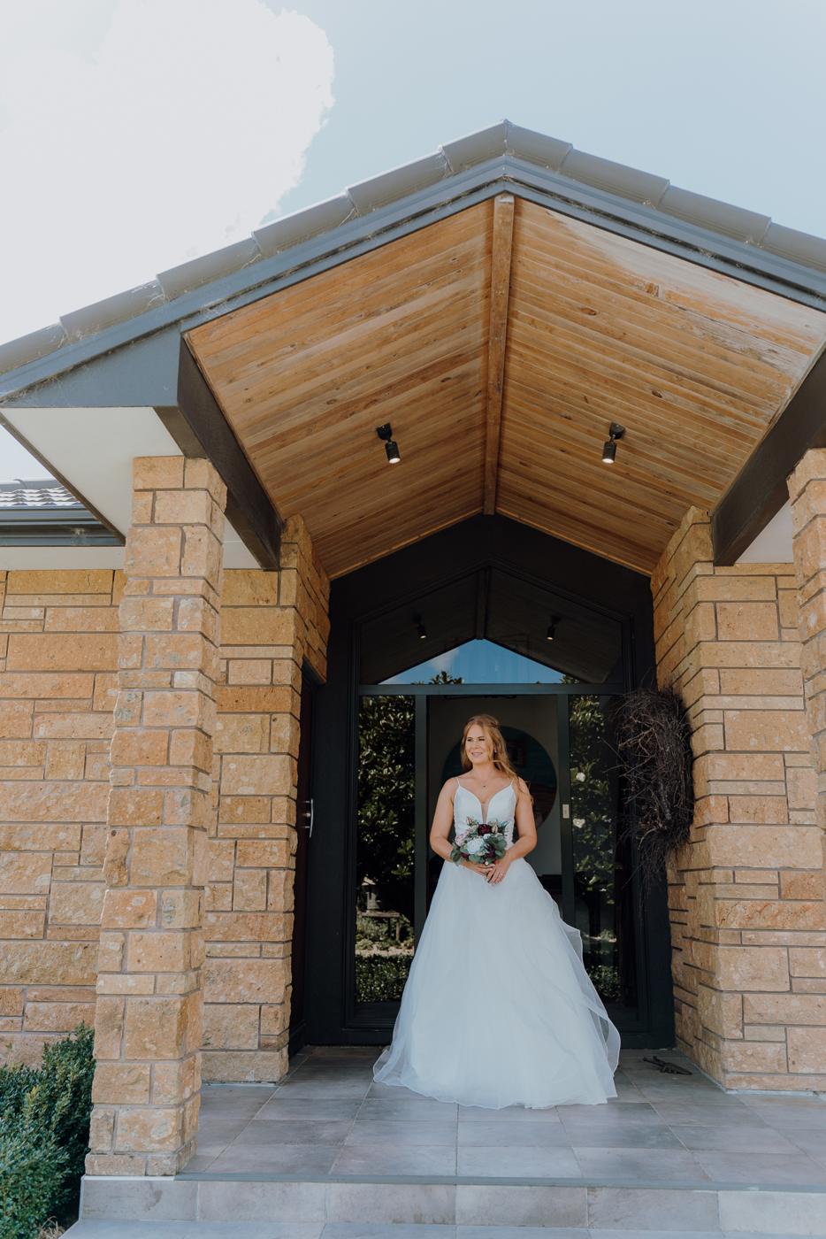 A bride standing in a doorway holding her bouquet