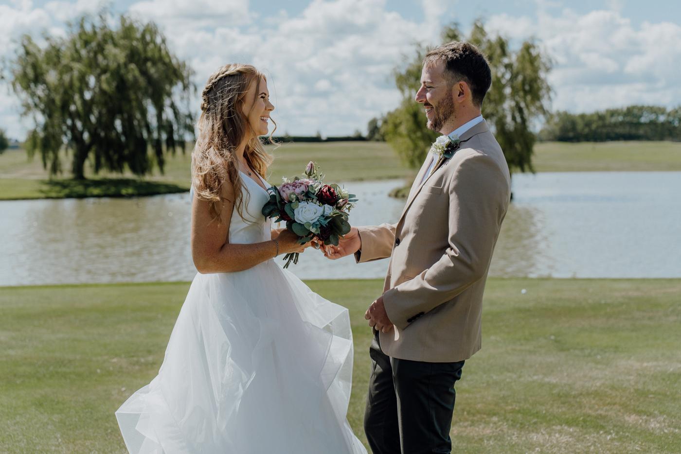A bride and groom seeing each other for the first time beside a lake
