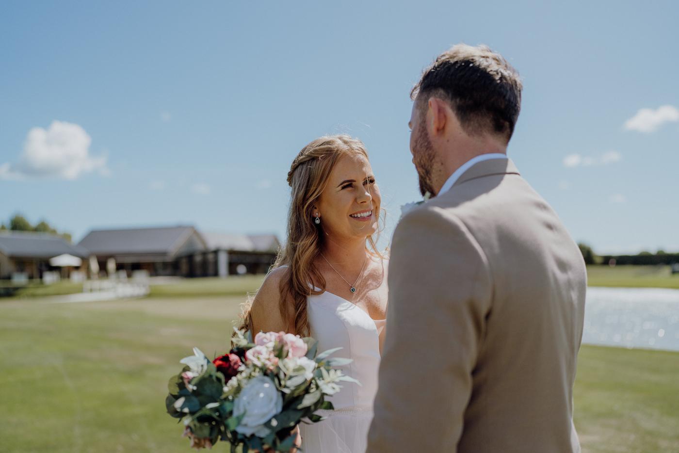 A bride and groom smiling at each other during the first look