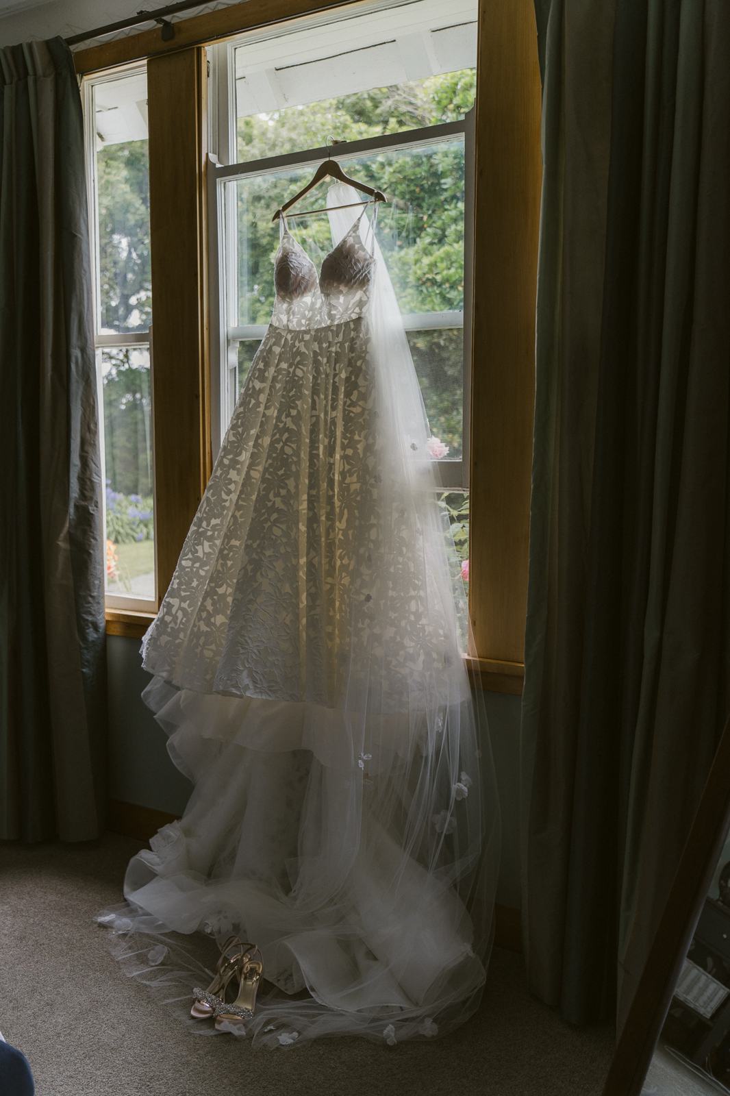 A wedding dress and veil hanging in a tall window