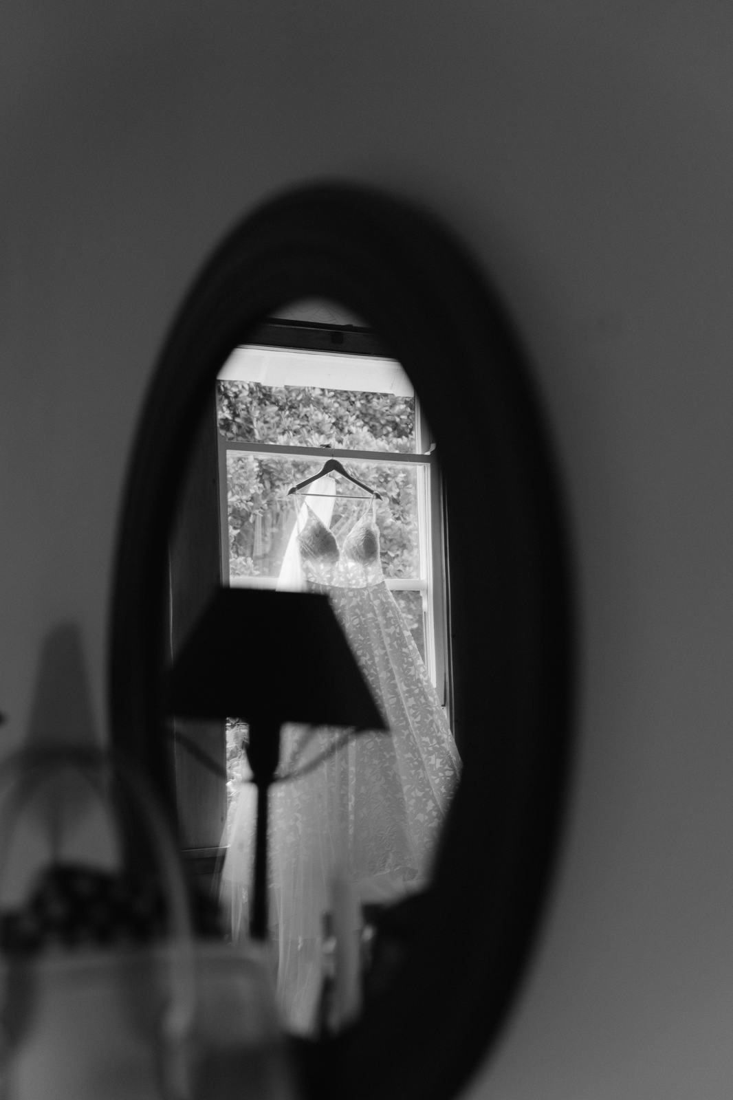 A wedding dress reflected in a round mirror in a quiet room