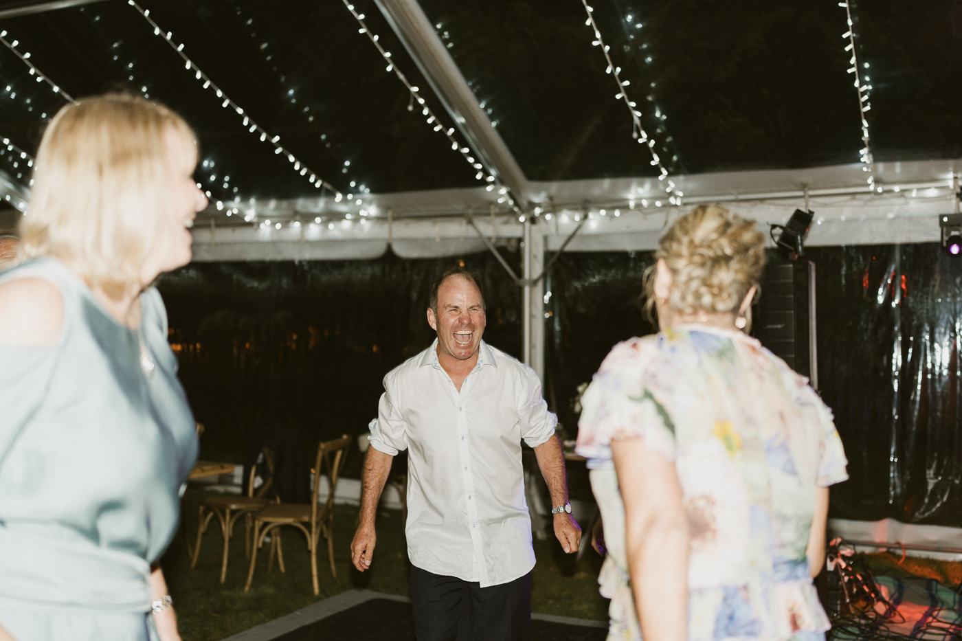 Guests dancing and laughing under string lights