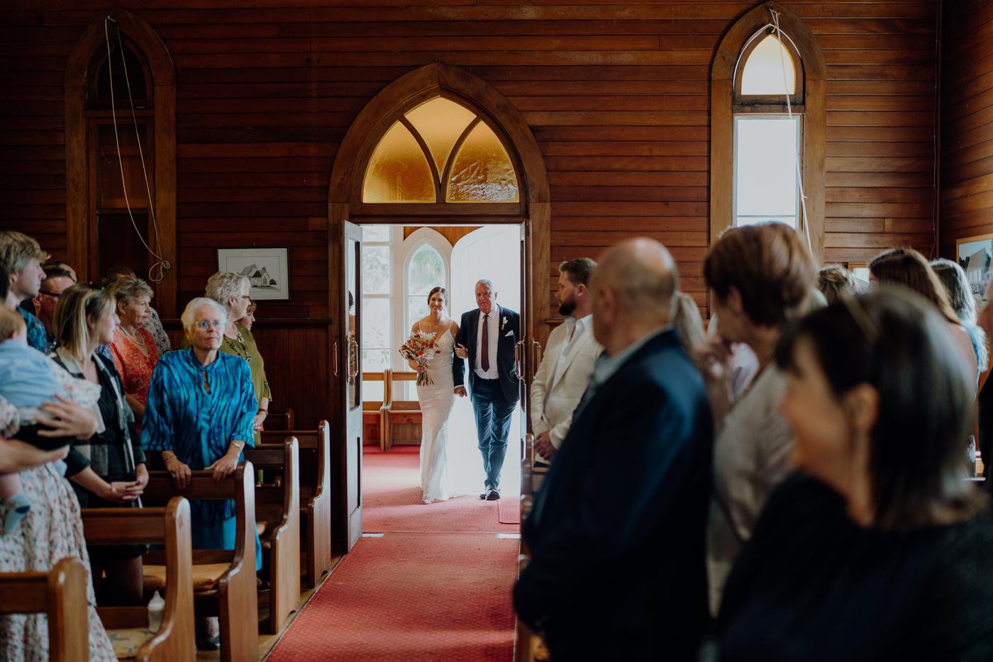 A bride walking up the aisle of a timber church