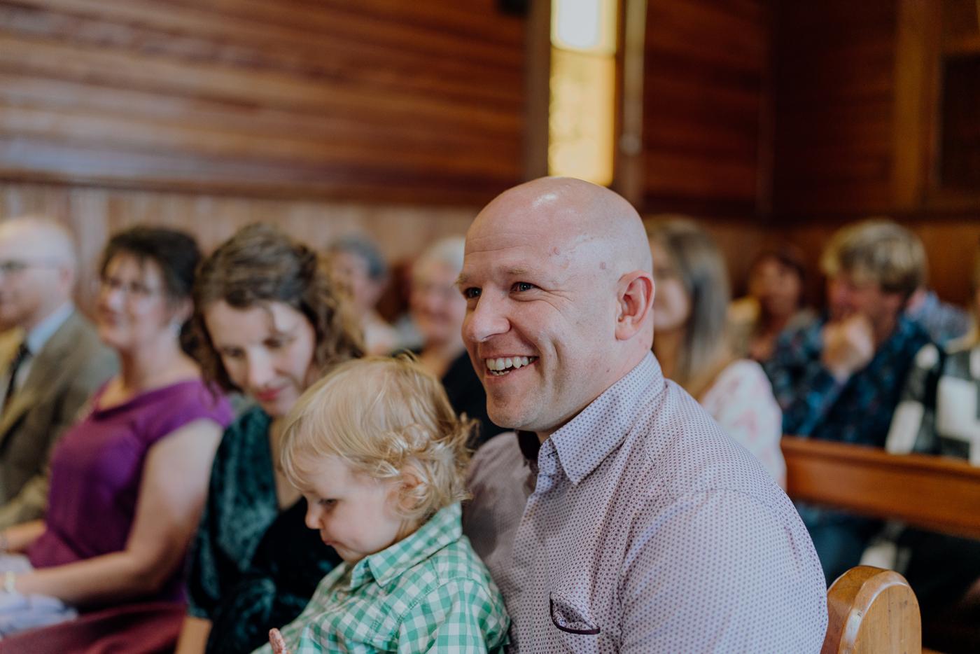 Guests smiling in the pews, a toddler on a lap