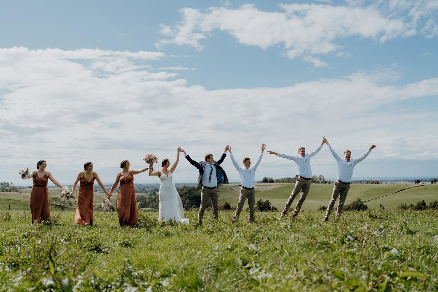 A bridal party jumping on a hilltop