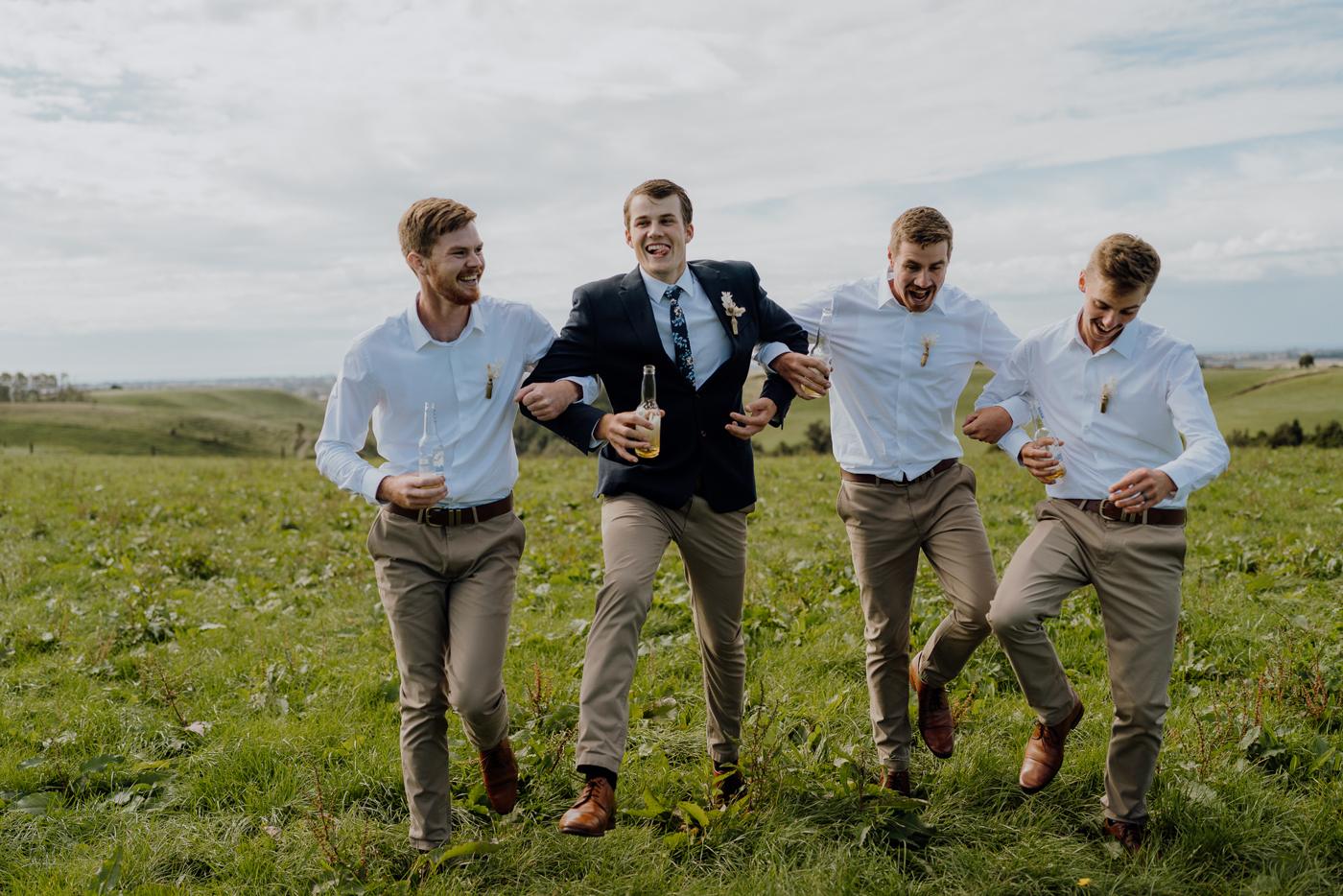 Groomsmen walking arm in arm across a field