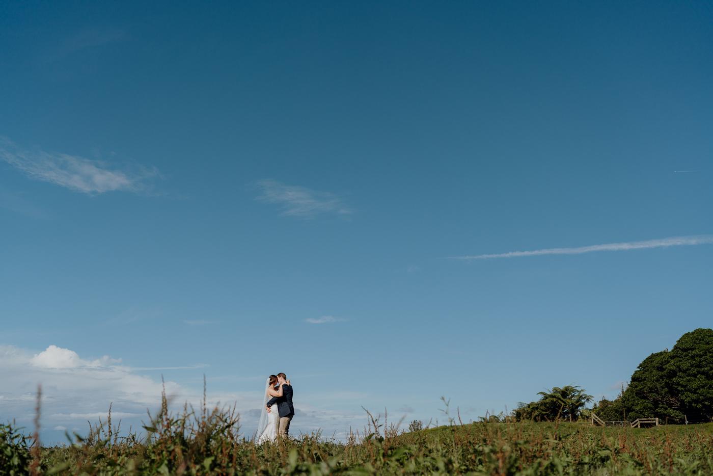 A couple tiny against a big blue sky on a hill