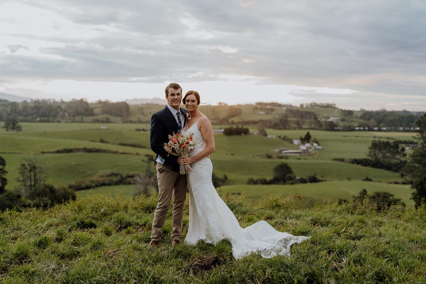 A couple on a green farm hill at evening