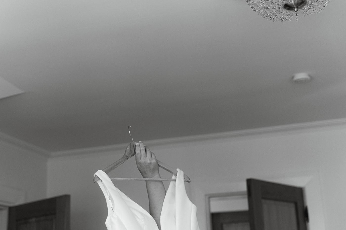 A wedding dress hanging in a bedroom, in black and white