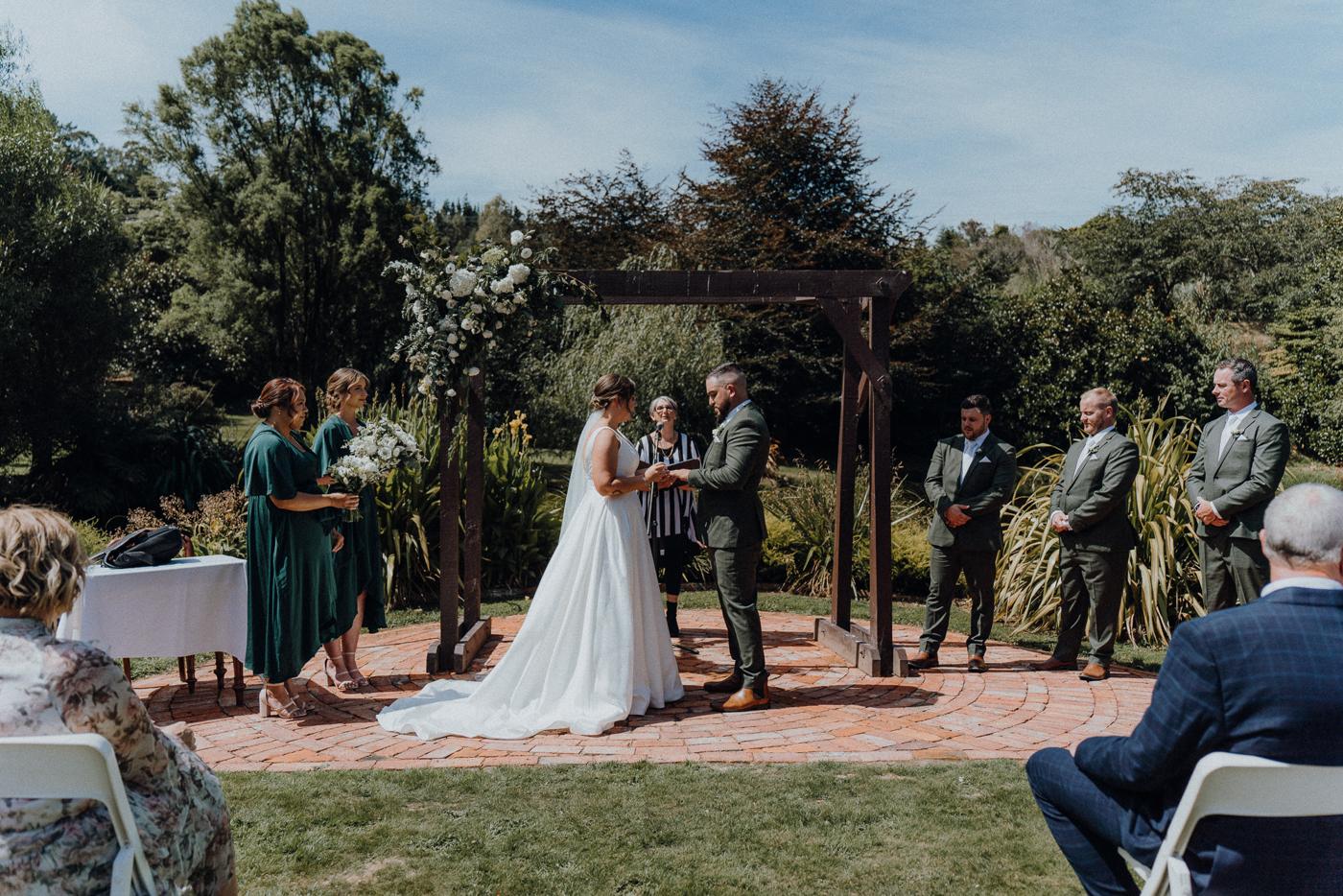 An outdoor ceremony under a timber pergola with guests around