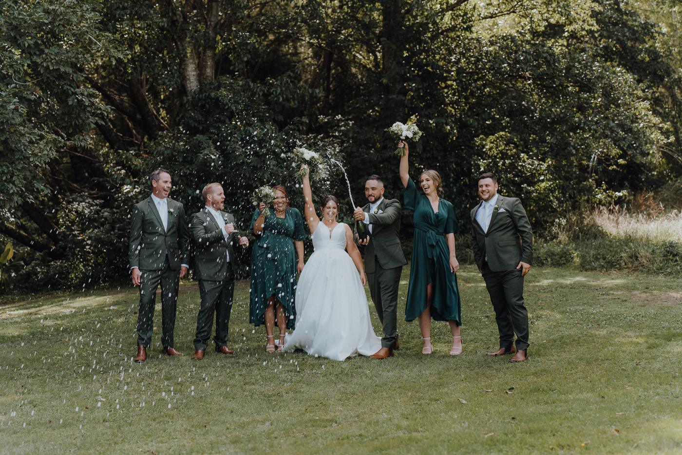 Bridal party jumping together on a lawn