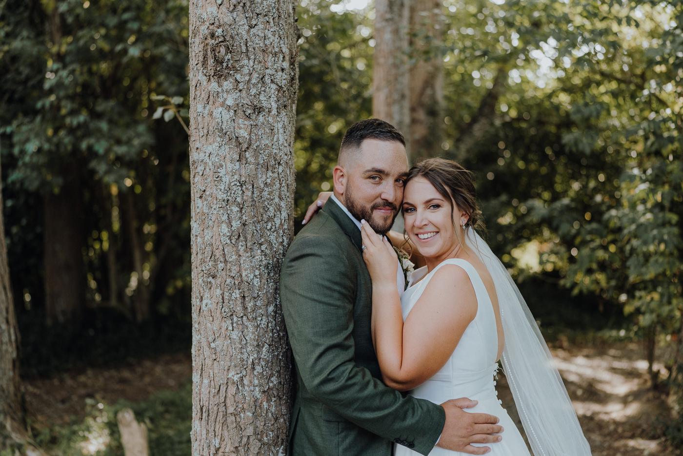 A couple leaning against a tree trunk, laughing