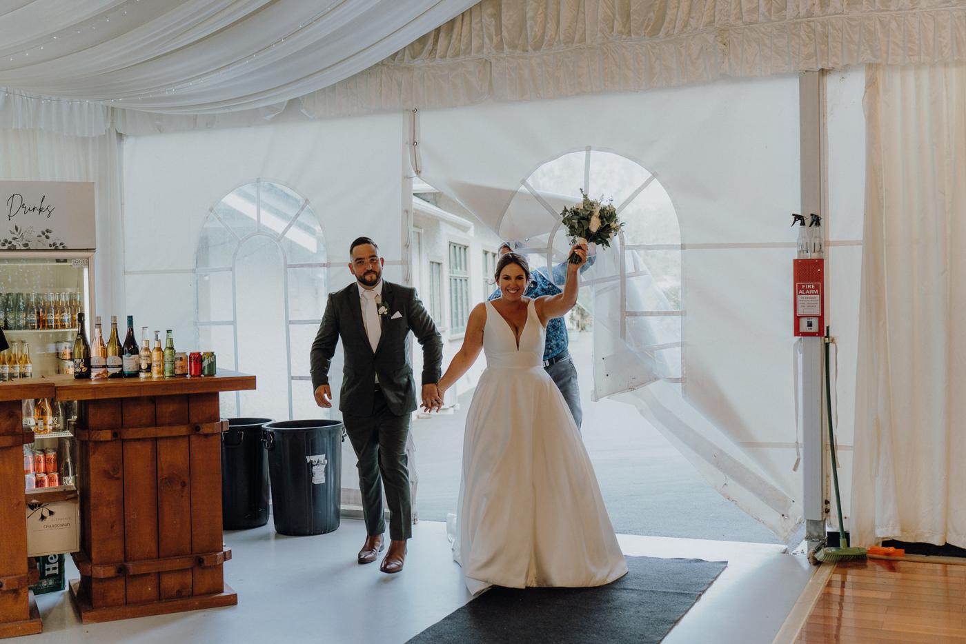 A bride and groom entering their reception hand in hand