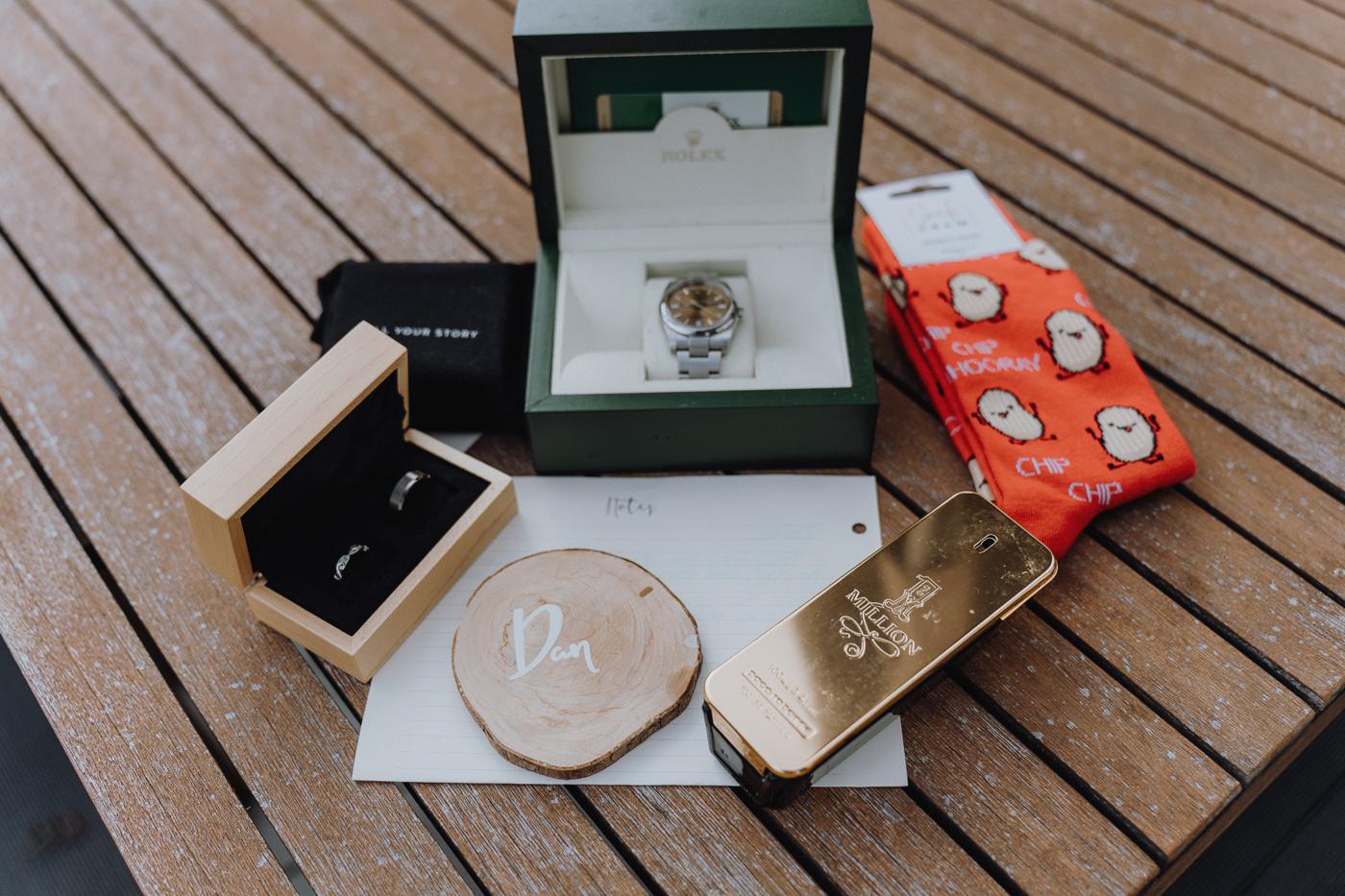 A groom's watch, rings and socks laid out on a deck