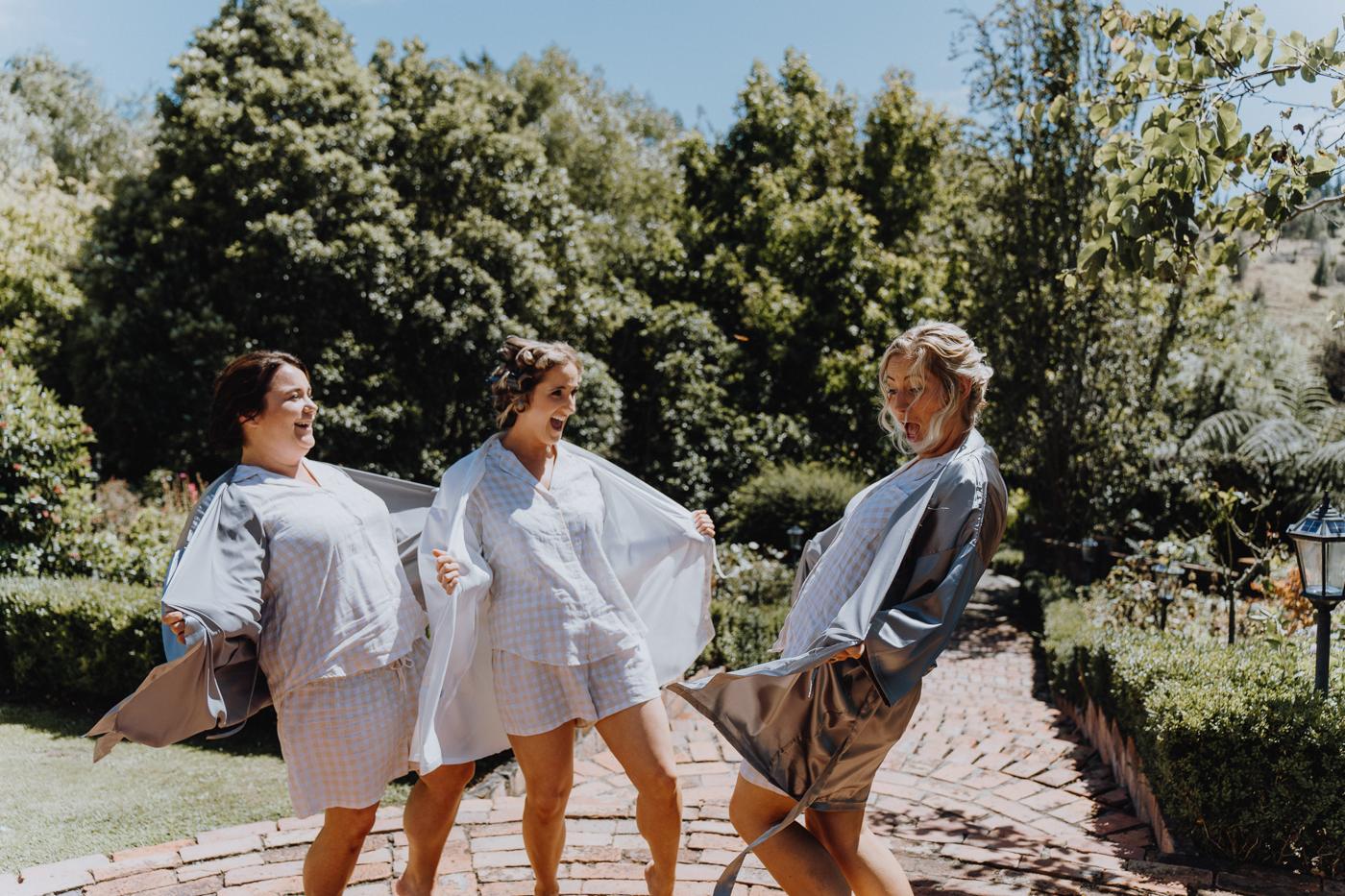 Women in robes laughing and dancing along a paved path