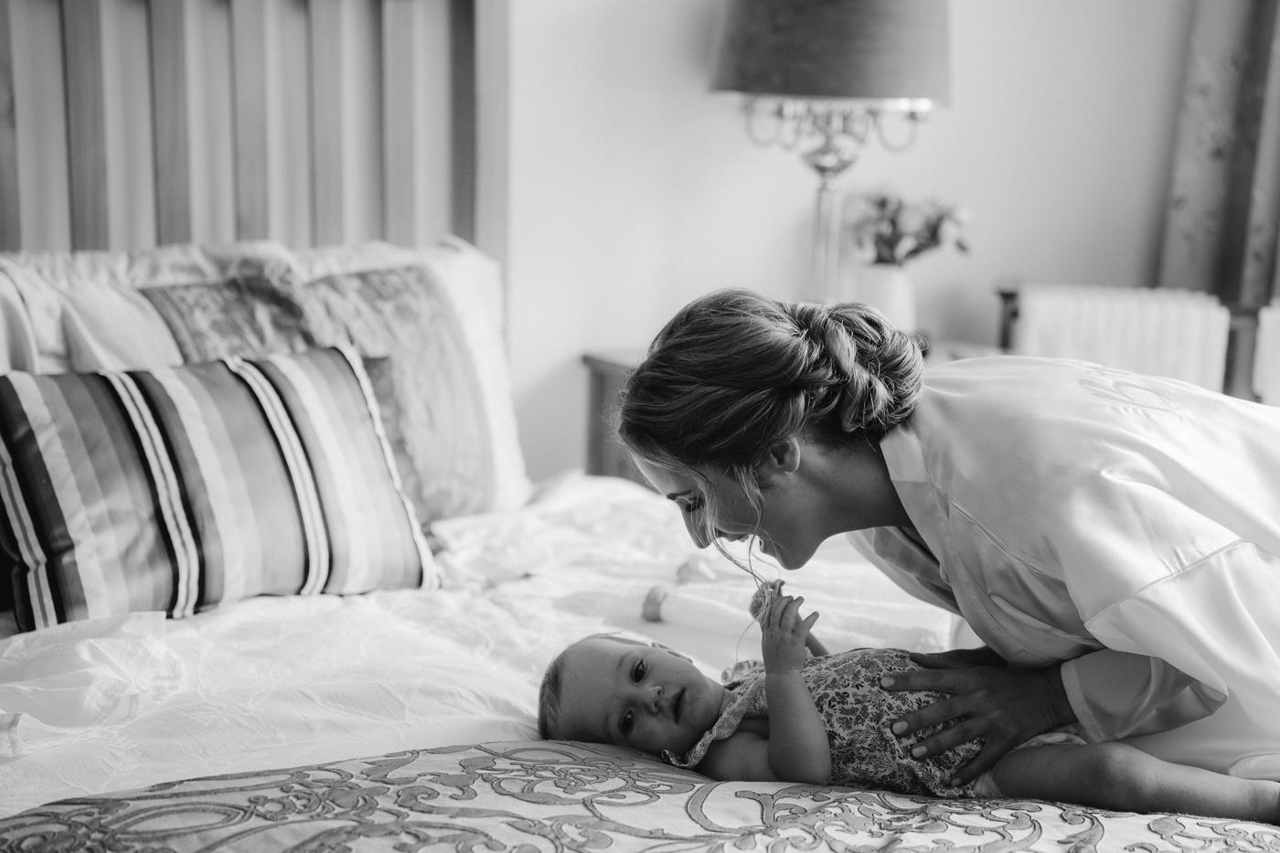 A bride playing on a bed with her baby, in black and white