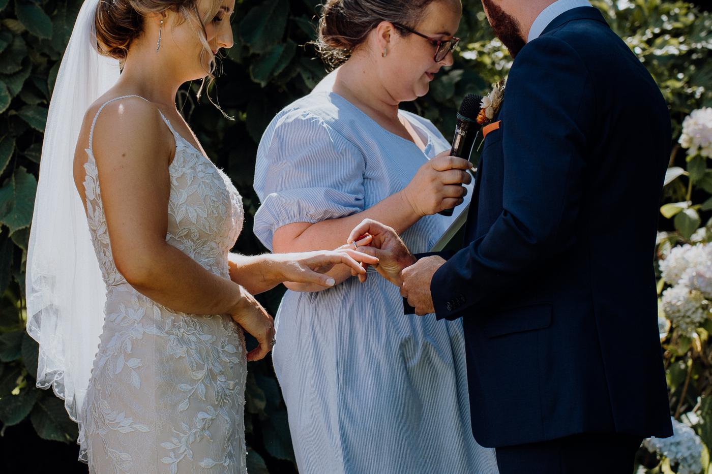 A bride and groom exchanging rings with a celebrant