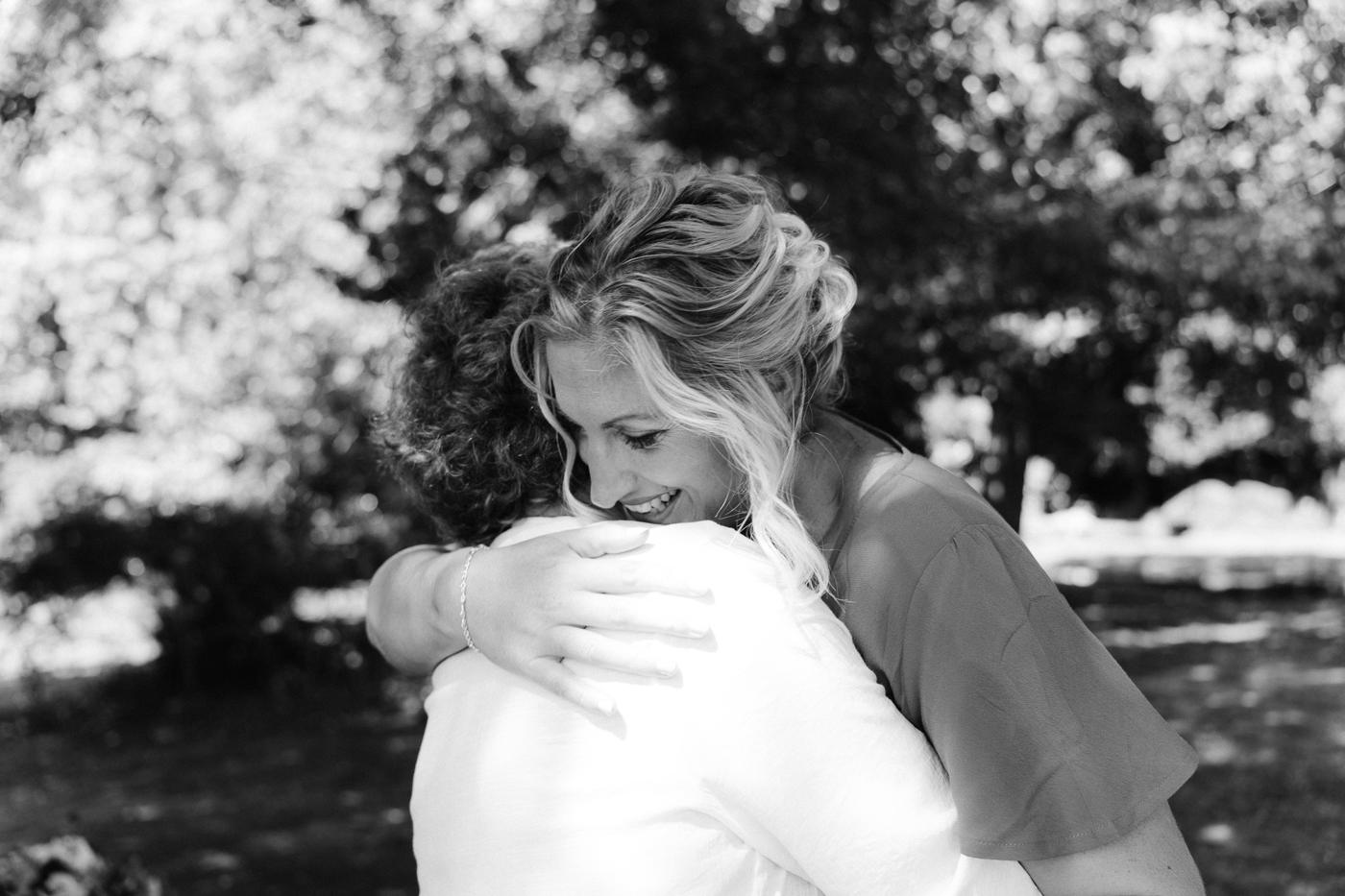 A bride hugging a guest in black and white