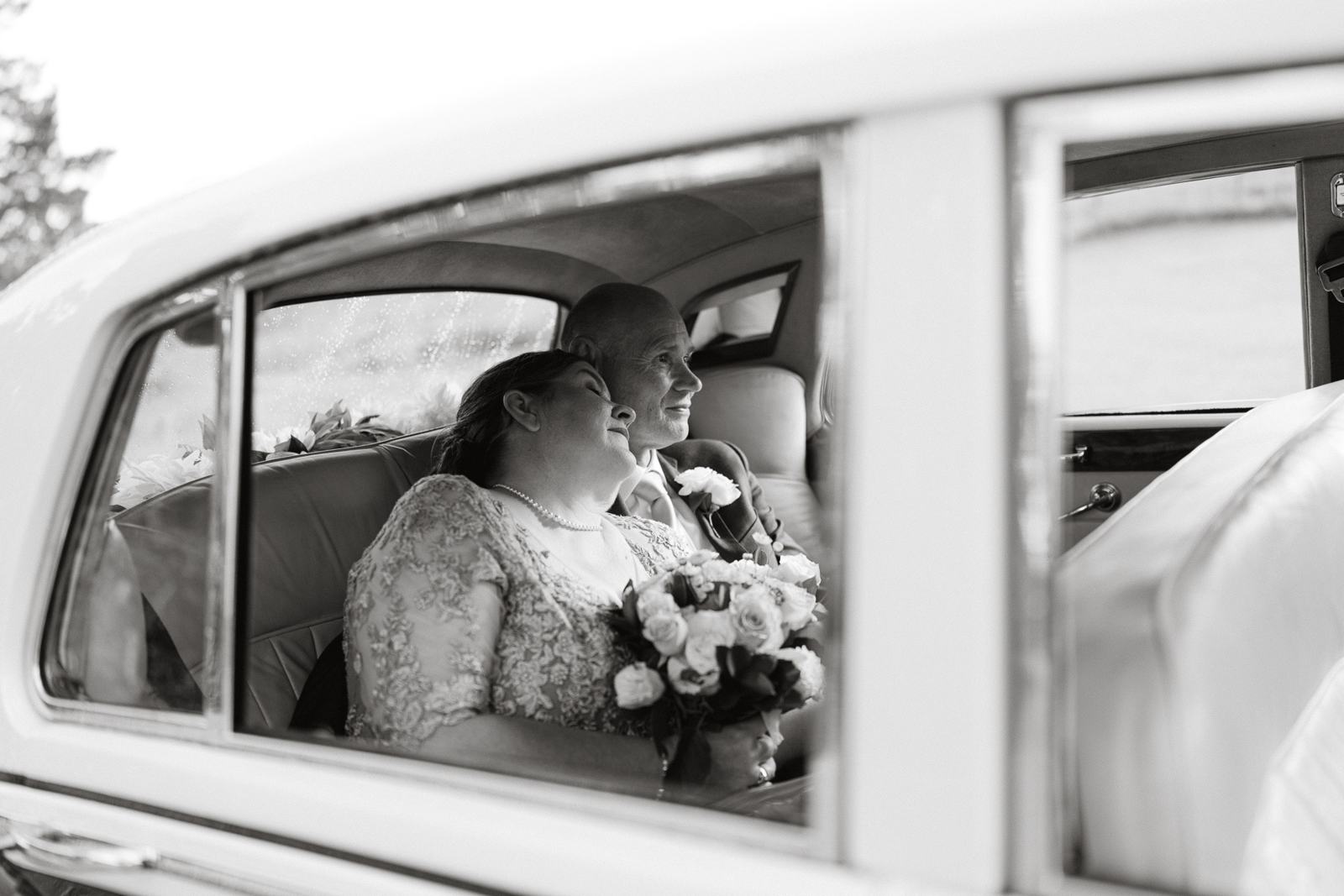 A bride in a vintage car seen through the window, in black and white