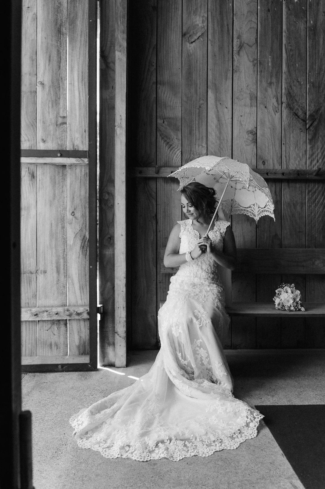 A bride holding a parasol in an old wooden doorway, black and white