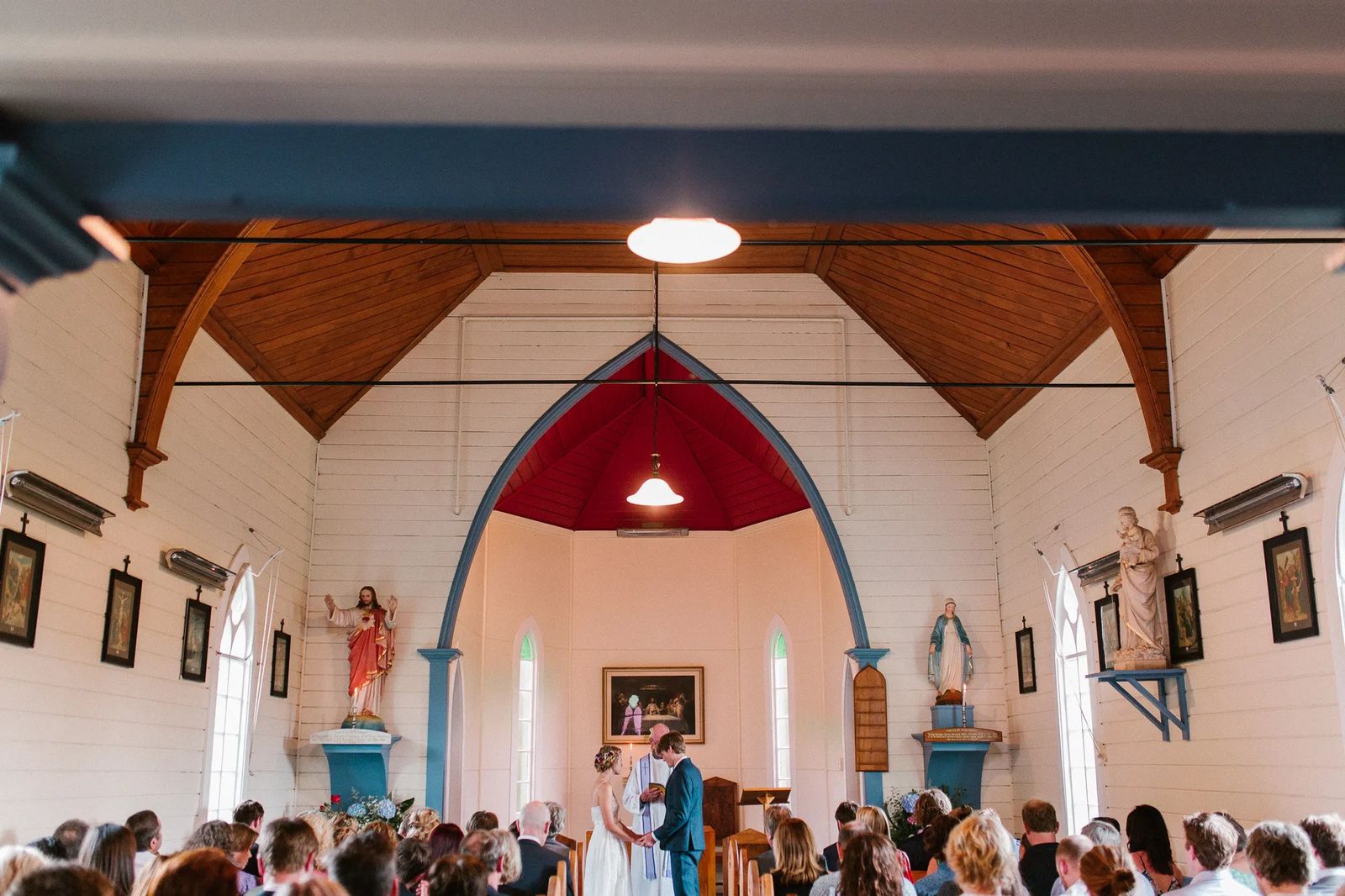 A wedding ceremony inside a small wooden church with guests filling the pews